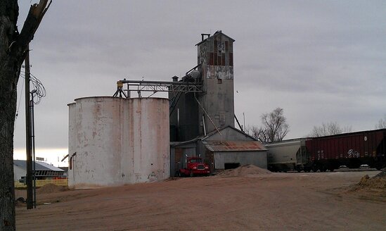 Old grain elevators standing beside railroad tracks in rural Colorado